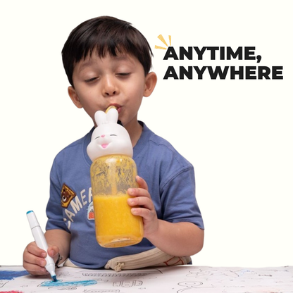 Boy drinking Yellow Smoothie Mix from bunny bottle while coloring