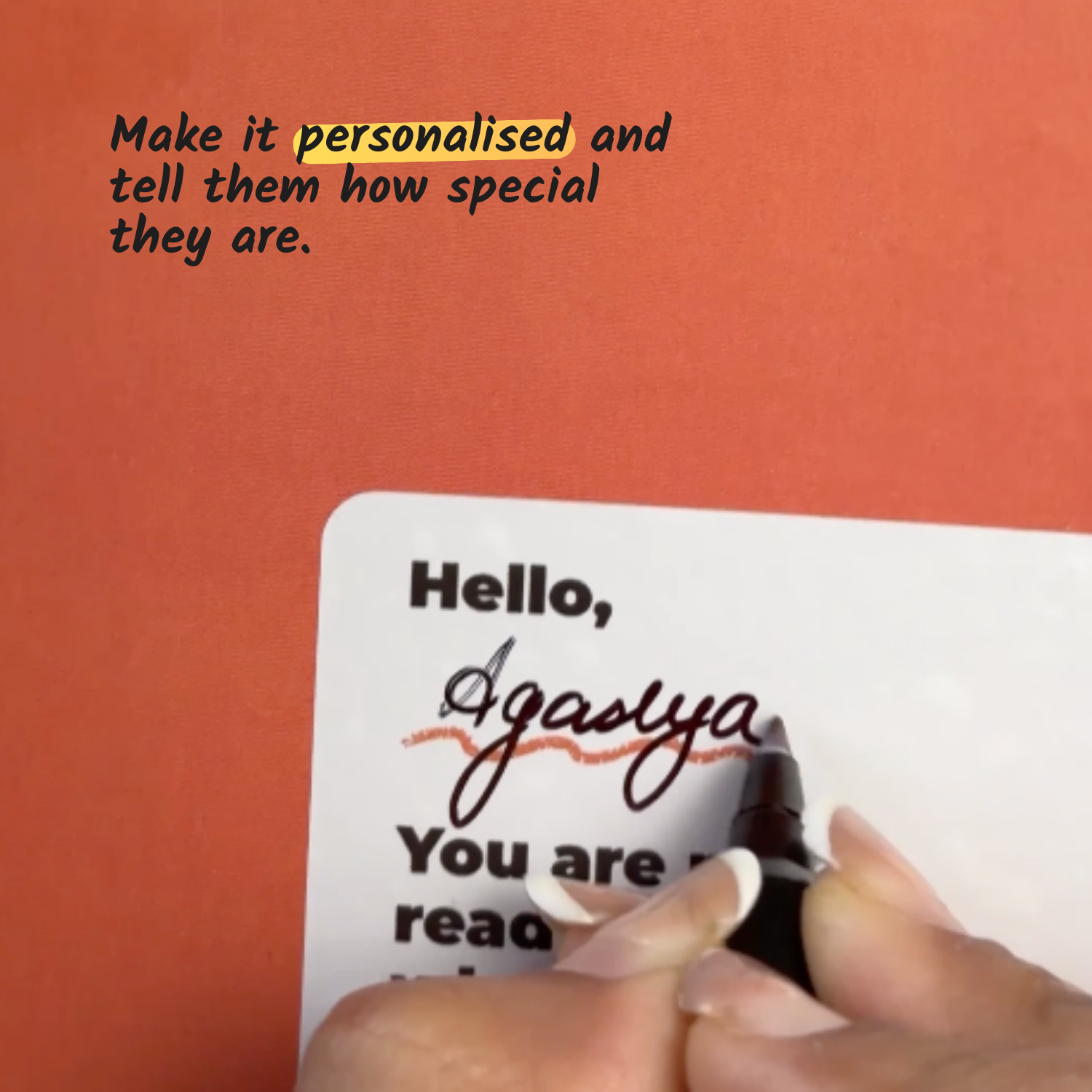 Hand writing on a card with personalized message against an orange background