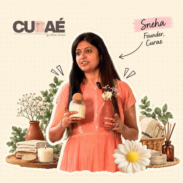 Sneha, founder of Curae, holding a handmade soy wax candle among dried flowers and a white daisy
