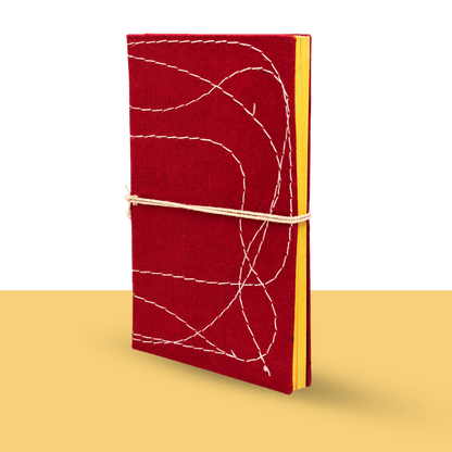 Hand-stitched bahi khata by CA Komal Modi, a traditional Indian account book with a red cloth cover, white thread stitching and yellow pages, tied with a cotton cord, for the Diwali new year pooja