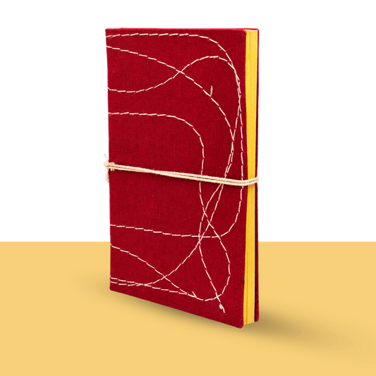 Hand-stitched bahi khata by CA Komal Modi, a traditional Indian account book with a red cloth cover, white thread stitching and yellow pages, tied with a cotton cord, for the Diwali new year pooja