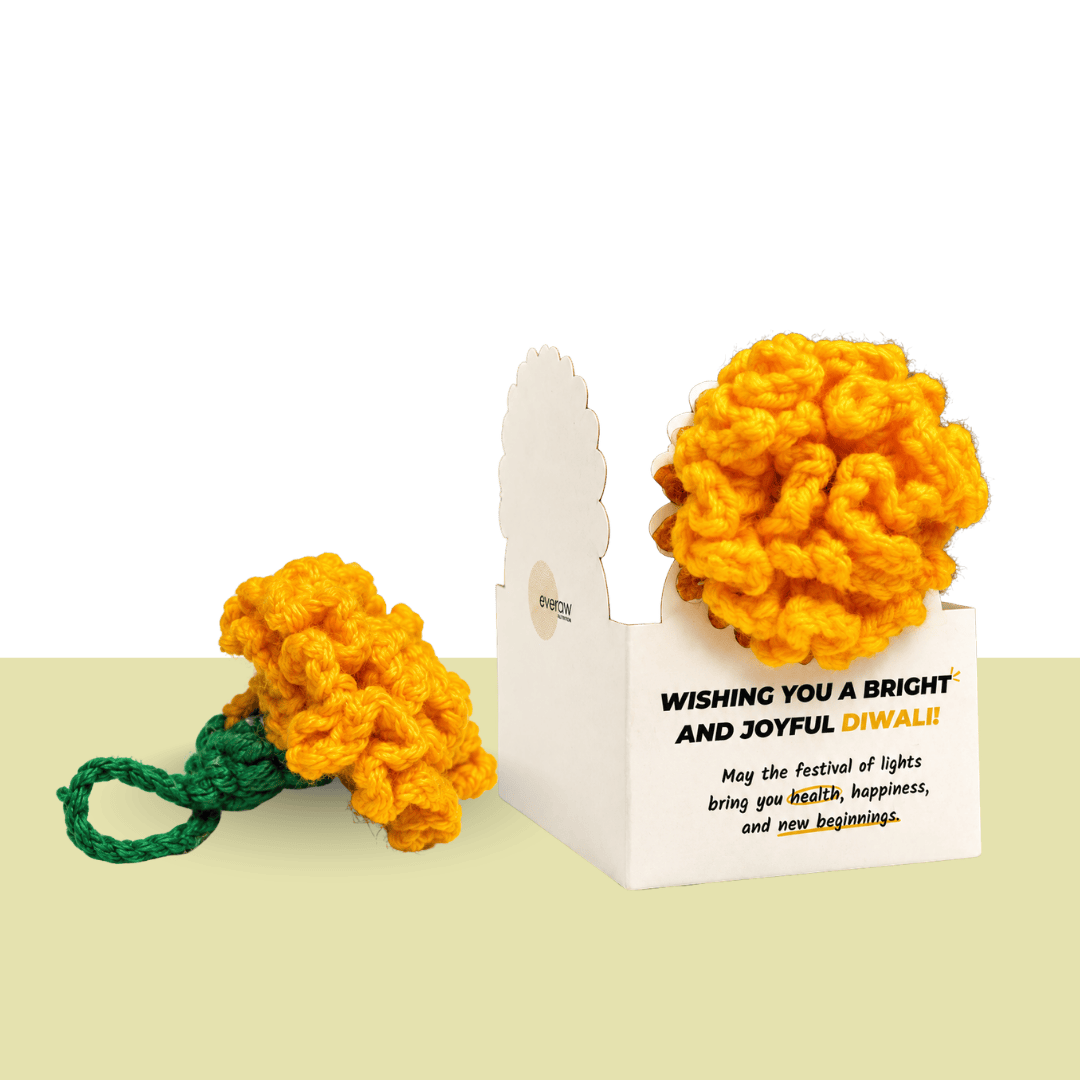 Handmade orange crochet marigold flower with a green stem beside a Diwali greeting card, made by the women of Surabhi, an Ajmer NGO that creates jobs for women with no family support
