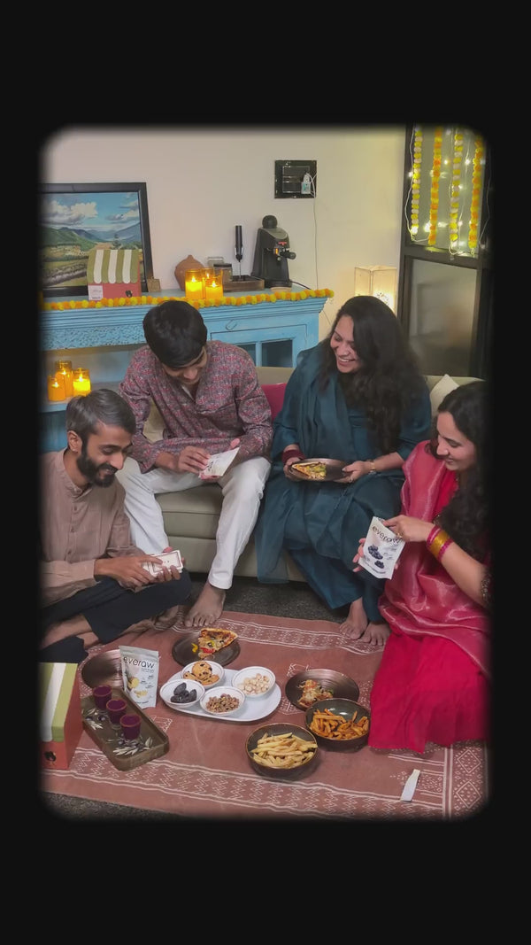 Friends at a Diwali get-together unwrapping the Everaw hamper, reading the Diwali card, a crochet marigold, a bahi khata and a candle, laughing together under fairy lights