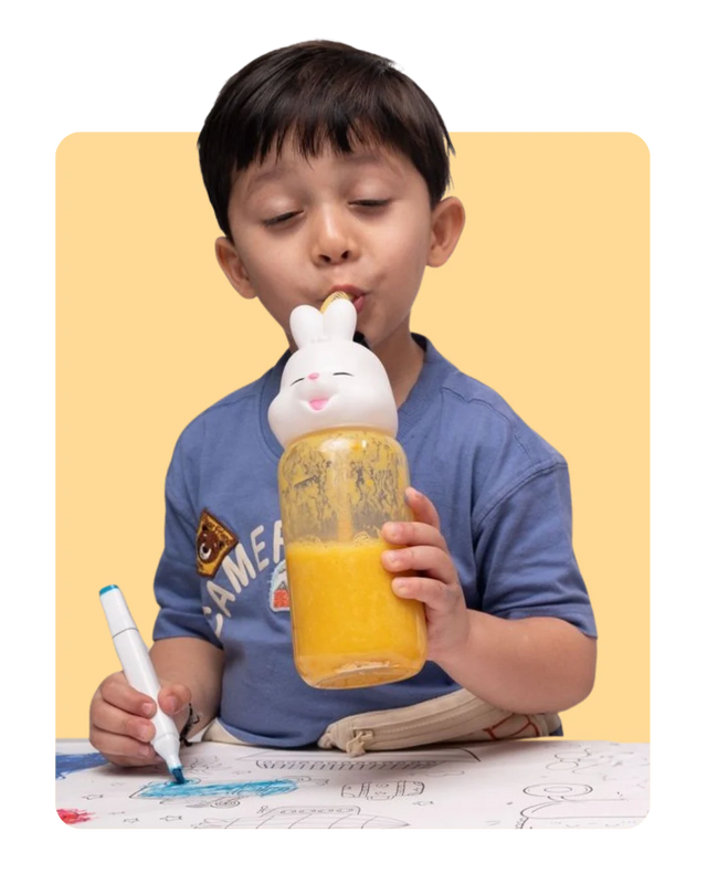Young boy drinking a mango Everaw smoothie from a bottle while colouring, a kid friendly smoothie with no added sugar